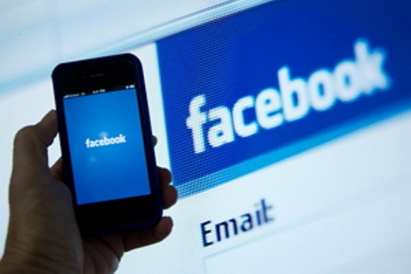 (FILES) In this May 10, 2012 file photo, a view of and Apple iPhone displaying the Facebook app's splash screen in front of the login page on a computer are shown in Washington, DC.  Facebook on June 15, 2015 unveiled a new feature that allows smartphone users to privately share photos of friends, by sifting through images with facial recognition technology. The standalone app, called Moments, allows users to share photos with friends who are in them, and to get images of themselves. "It's hard to get the photos your friends have taken of you, and everyone always insists on taking that same group shot with multiple phones to ensure they get a copy," product manager Will Ruben said in a blog post.  AFP PHOTO / KAREN BLEIER /FILES